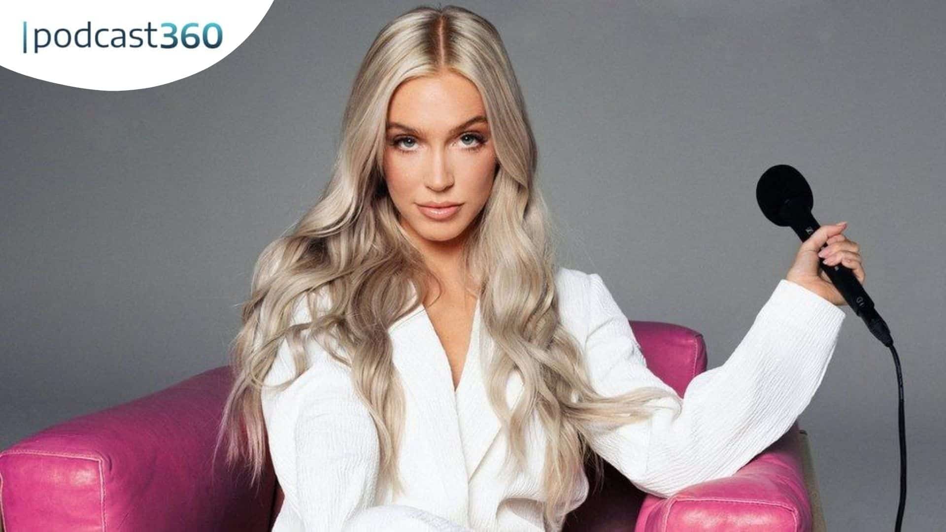 Eine Frau in Weiß sitzt auf einem rosafarbenen Stuhl und hält ein Mikrofon in der Hand, in der Ecke ist ein "podcast360"-Logo zu sehen.