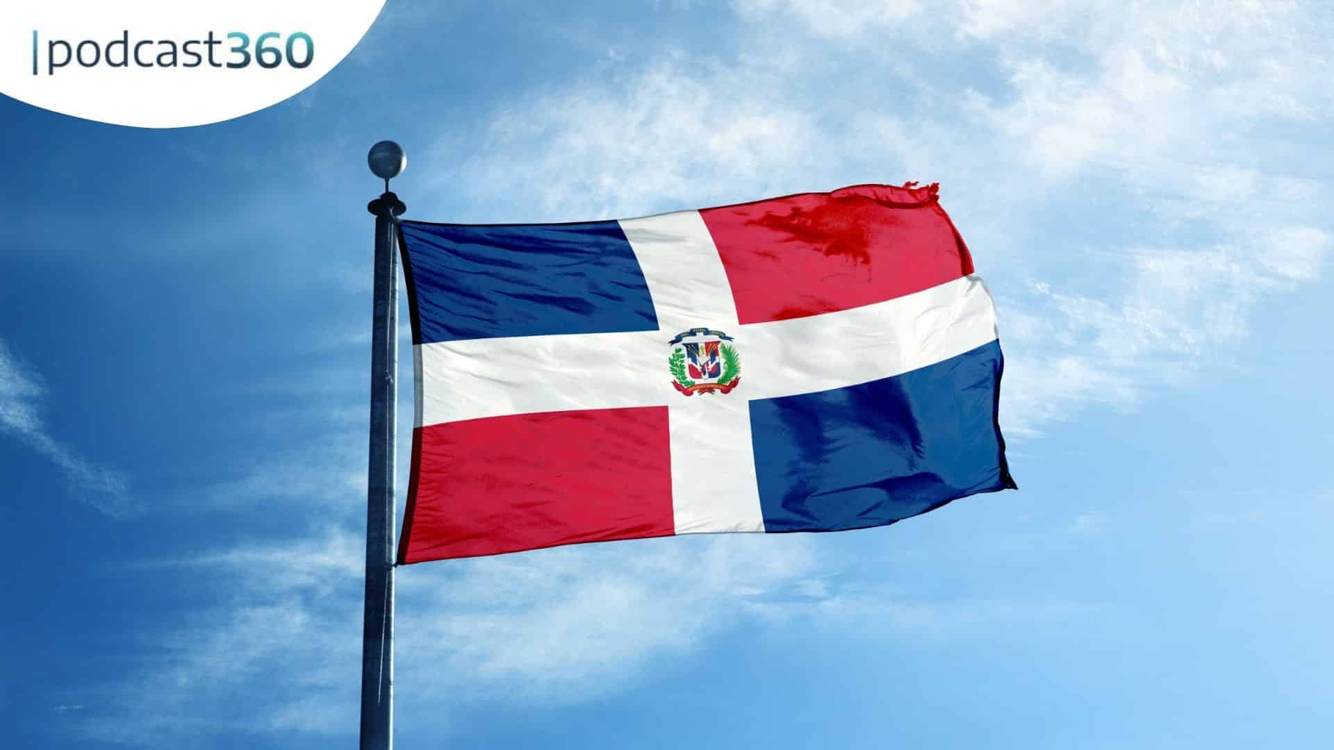 Die Flagge der Dominikanischen Republik weht vor einem blauen Himmel mit dem Text "podcast360" in der Ecke.