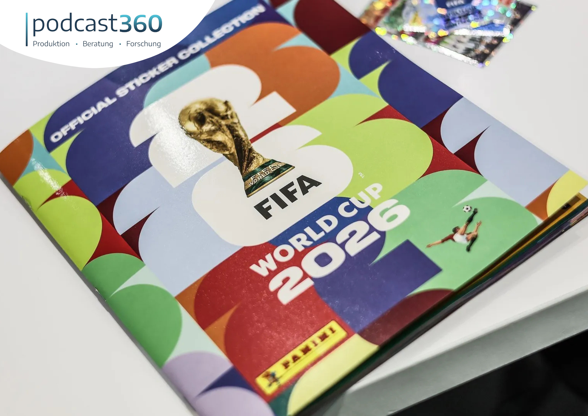 Das Stickeralbum zur FIFA-Weltmeisterschaft 2026 mit farbenfrohem Einband und Stickerpackungen auf einem weißen Tisch – ein unverzichtbares Sammlerstück, das die Spannung der Fußball-WM einfängt und modernes Marketing im Bereich der Sport-Sammlerstücke präsentiert.